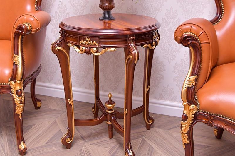 Carved wooden side table between two upholstered chairs