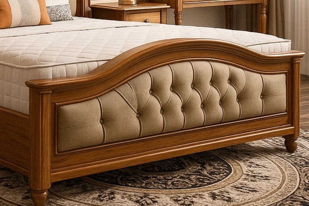 Wooden bed with an arched, button-tufted footboard in a furnished bedroom