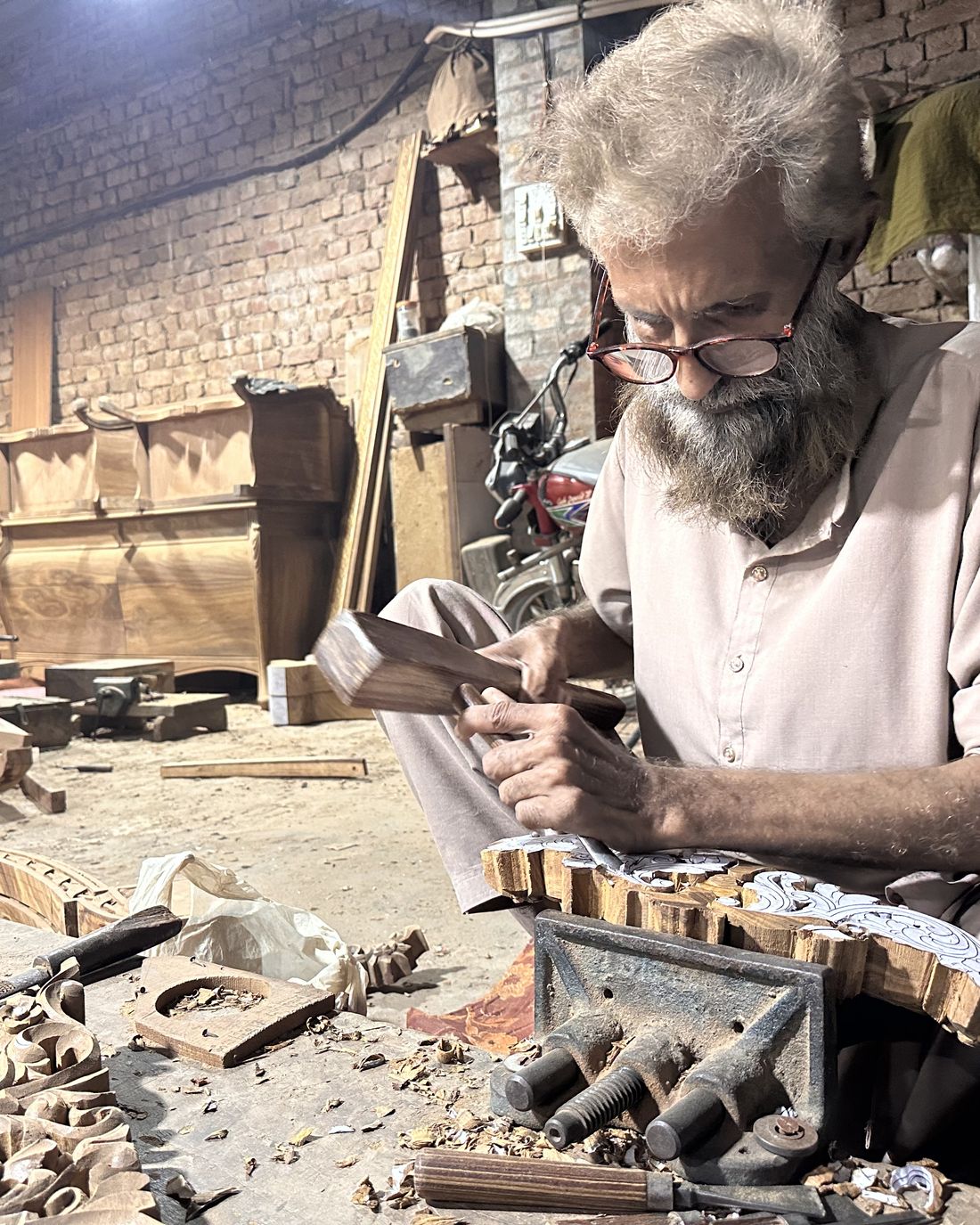 A senior craftsman carving wood in the Chiniot workshop