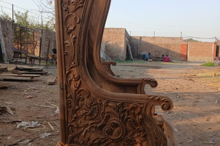 Deep-carved high-back chair — side view in the workshop