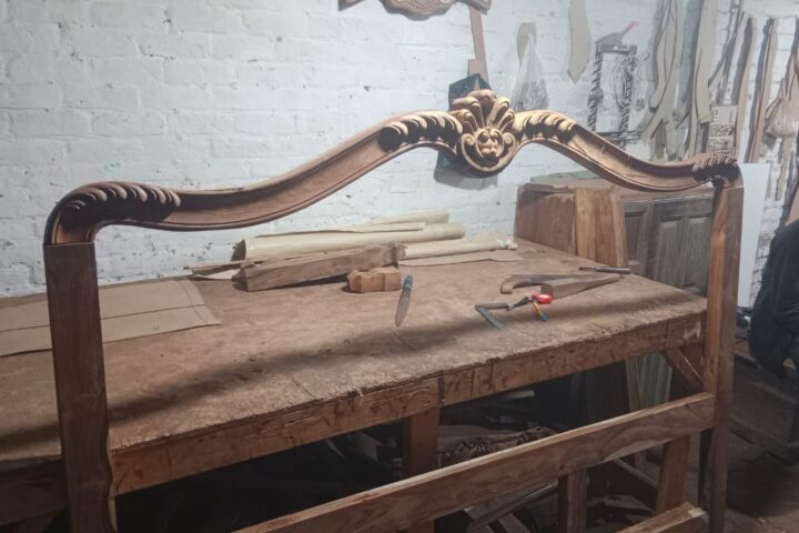 Floral crest carved bed — headboard on the workbench